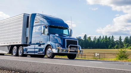 Large blue semi-truck pulling freight trailer on rural highway in 18-wheeler accident case