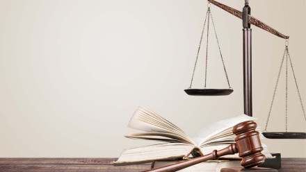 Wooden gavel resting on open legal book beside scales of justice representing civil litigation