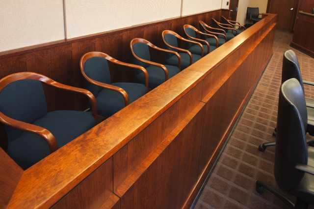 Empty jury box with navy upholstered chairs along polished wood railing in modern criminal defense courtroom