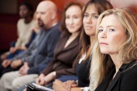 Diverse group of attentive jurors seated in row during criminal defense trial proceedings