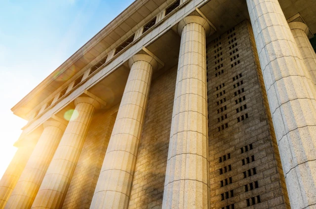 Stone courthouse with tall columns bathed in sunlight representing access to criminal defense legal justice