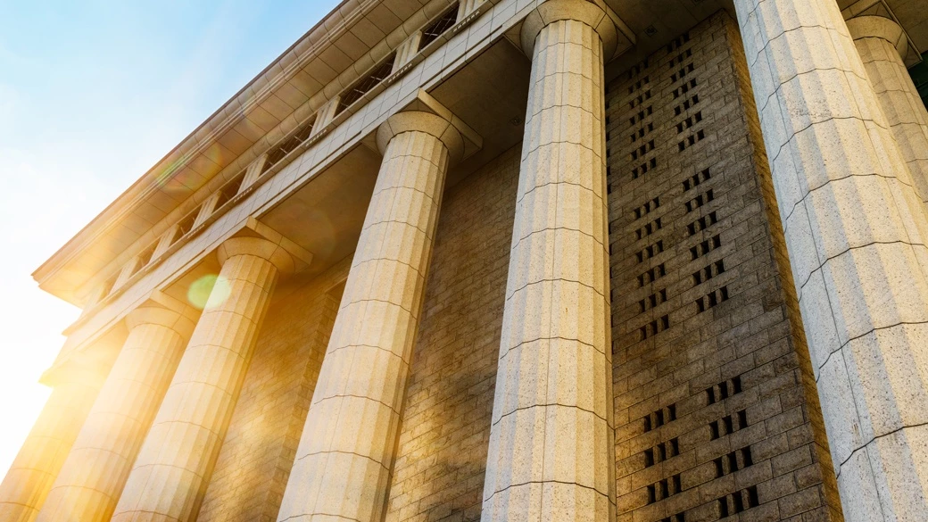 Stone courthouse with tall columns bathed in sunlight representing access to criminal defense legal justice