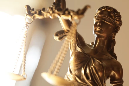 Gold Lady Justice figurine with scales photographed against bright light symbolizing criminal defense fairness