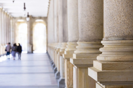 People walking through columned courthouse hallway representing access to criminal defense legal counsel