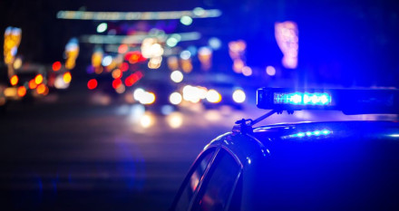 Police car blue emergency light flashing on city street at night during criminal arrest